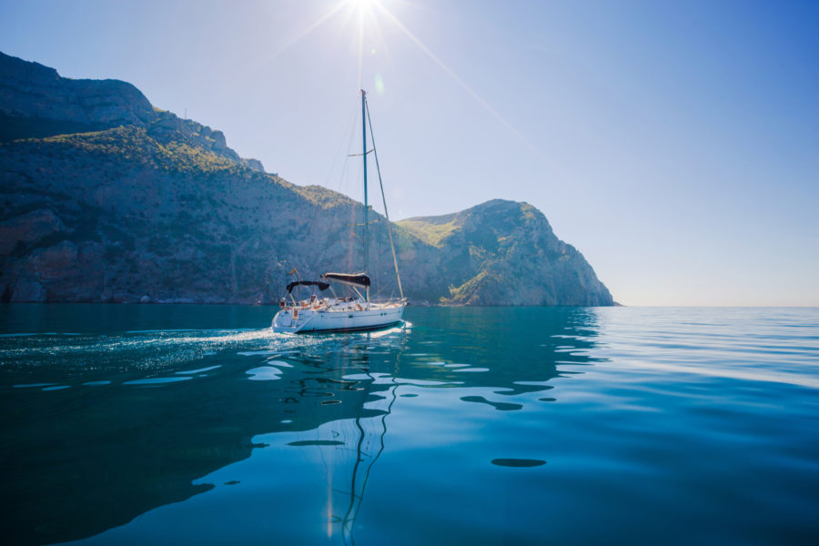 Large sailboat navigating around picturesque cliffs