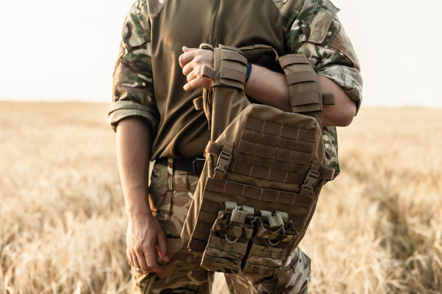 Soldier standing in field with backpack over arm