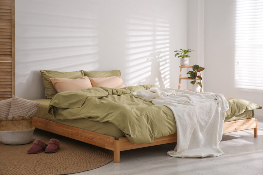 Minimalist bedroom with green and white bedding on bed